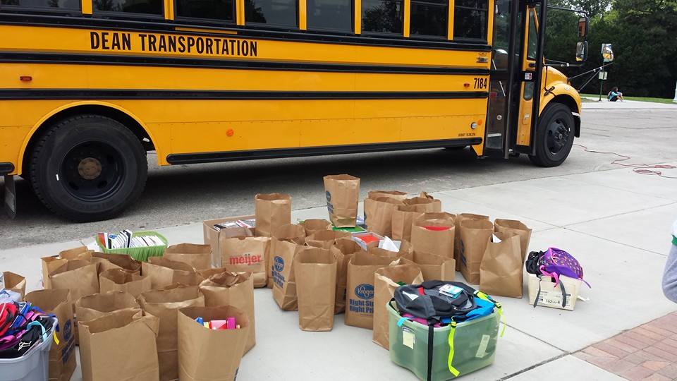 School bus ready to be loaded with bags of donated school supplies.